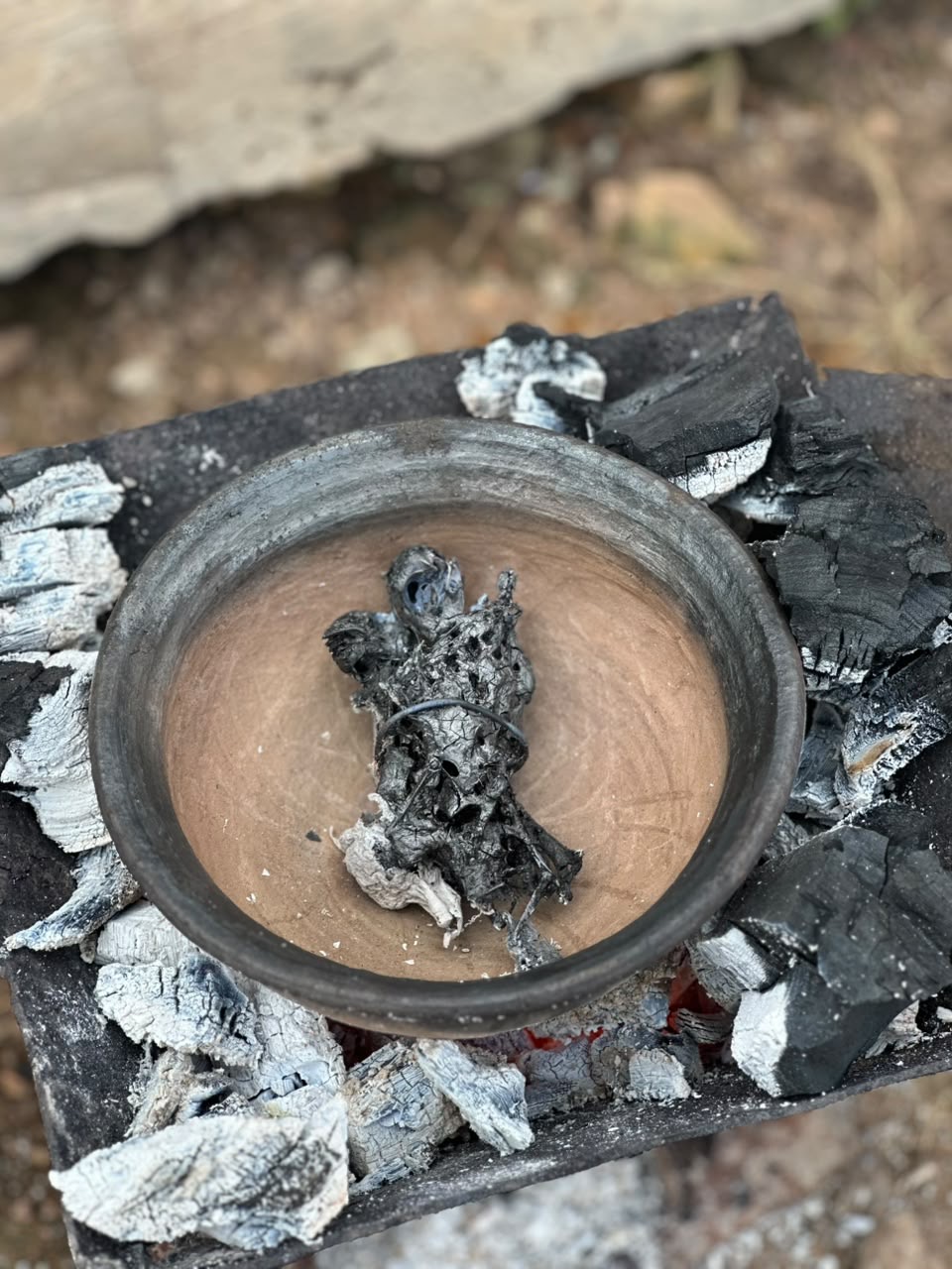 An earthen pot opened over the coals during preparation